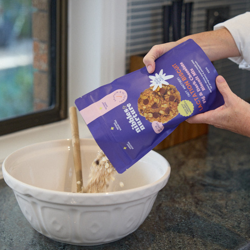 Pouring Nibbles & Nurture Fig & Dark Chocolate Lactation Biscuit Mix into a bowl for easy postpartum snack prep